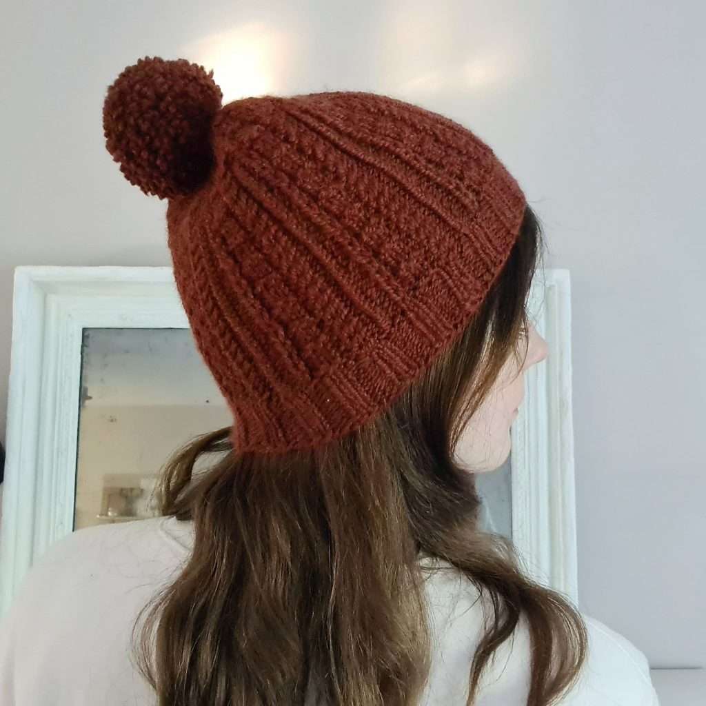 free Bosquet Hat knitting pattern featuring twisted stitches and small cables knit in aran weight yarn